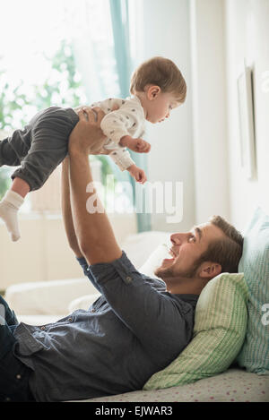 Happy father playing with little son (2-3 years) on bed Stock Photo