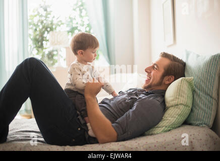 Happy father playing with little son (2-3 years) on bed Stock Photo