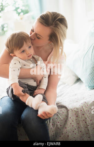 Mother kissing little son (2-3 years) on bed Stock Photo