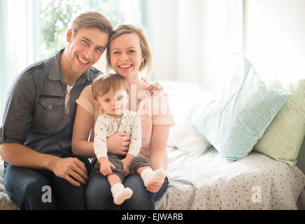 Happy parents with little son (2-3 years) sitting on bed Stock Photo