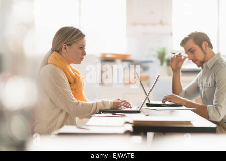 Young man and woman working at desk in office Stock Photo