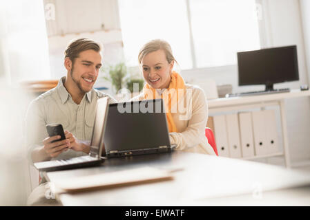Young man and woman working together with laptop in office Stock Photo