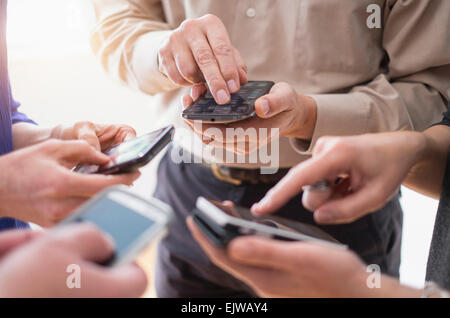 Close up of hands of men and women using smartphones together Stock Photo