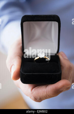 Close up of man's hand holding open box with engagement ring Stock Photo