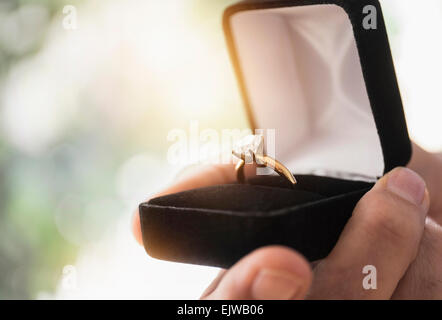 Close up of man's hand holding open box with engagement ring Stock Photo