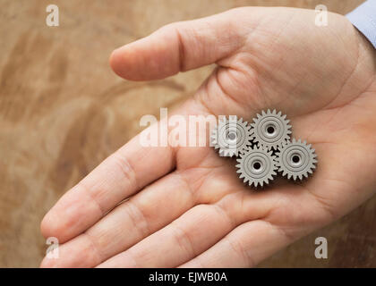 Close up of man's hand holding metal cogs Stock Photo