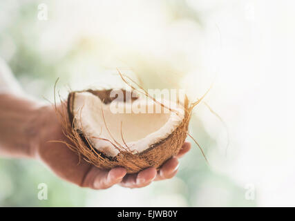 Close up of man's hand holding part of coconut Stock Photo