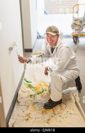 Portrait of smiling manual worker painting wall Stock Photo