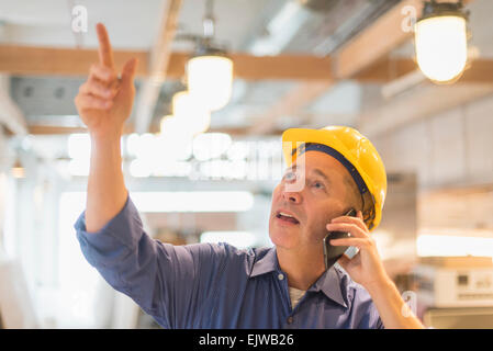 Architect in hardhat talking on mobile phone Stock Photo