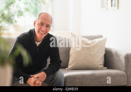 Portrait of smiling mature man relaxing on sofa in living room Stock Photo