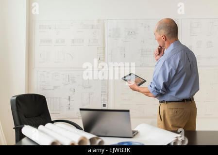 Mature architect looking at blueprints in office Stock Photo
