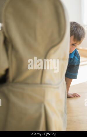 Boy (6-7) peeking around side of sofa Stock Photo