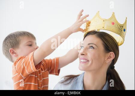 Son (6-7) putting crown to mother's head Stock Photo