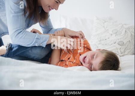 Mother and son (6-7) playing in bed Stock Photo
