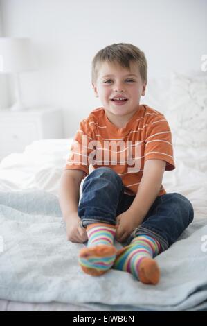 Portrait of boy (6-7) sitting on bed Stock Photo