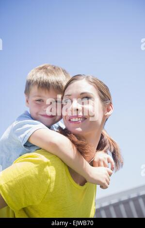 Mother giving her son (6-7) piggyback ride Stock Photo
