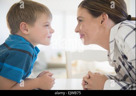 Mother and son (6-7) facing each other in domestic room Stock Photo