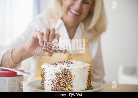 Senior woman decorating cake Stock Photo