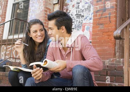 USA, New York State, New York City, Brooklyn, Young couple reading book and doing crossword Stock Photo