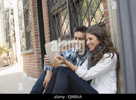 USA, New York State, New York City, Brooklyn, Couple using tablet on sidewalk Stock Photo