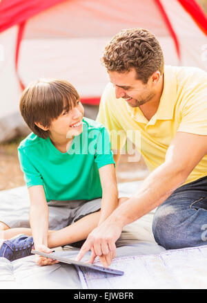 USA, Florida, Jupiter, Father and son (12-13) using digital table at camping Stock Photo