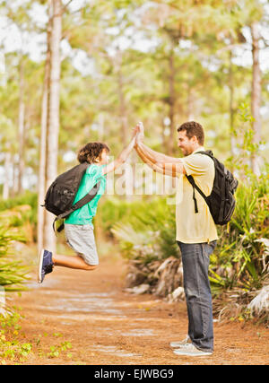 USA, Florida, Jupiter, Father and son (12-13) doing high five in forest Stock Photo