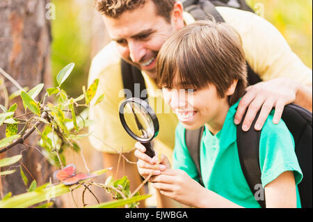 USA, Florida, Jupiter, Father and son (12-13) watching butterfly with magnifying glass Stock Photo