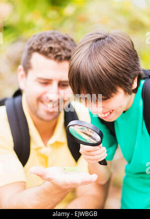 USA, Florida, Jupiter, Father and son (12-13) watching insect with magnifying glass Stock Photo