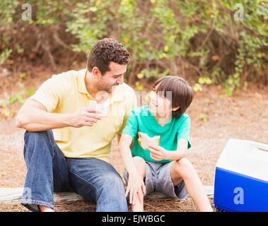 USA, Florida, Jupiter, Father and son (12-13) eating sandwiches in forest Stock Photo