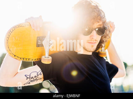 USA, Florida, West Palm Beach, Man holding skateboard on his arms Stock Photo