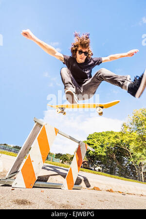 USA, Florida, West Palm Beach, Man jumping on skate board in construction site Stock Photo
