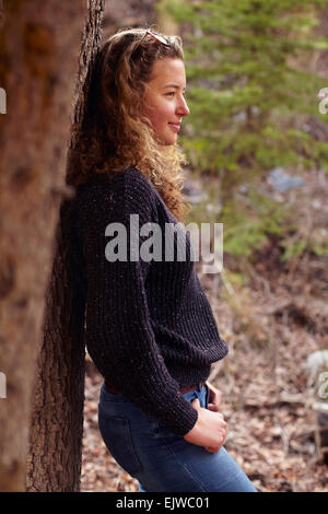 USA, Colorado, Portrait of young woman leaning on tree Stock Photo