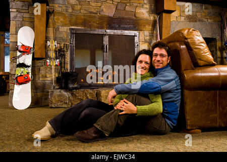 USA, Montana, Whitefish, Man and woman hanging out in front of fireplace Stock Photo