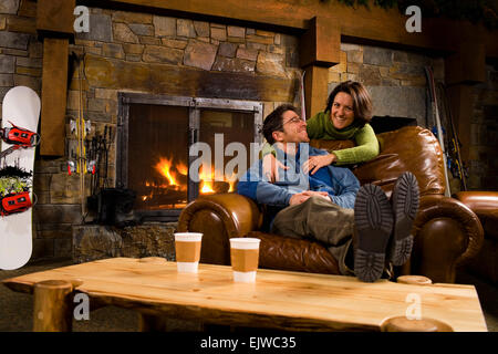USA, Montana, Whitefish, Man and woman hanging out in front of fireplace Stock Photo