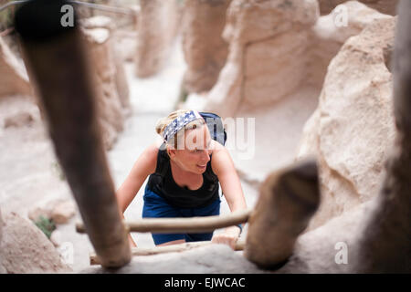 USA, New Mexico, Bandelier National Monument Los Alamos, Woman walking up ladder Stock Photo