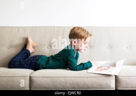 Boy (2-3) reading book on sofa Stock Photo