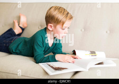 Boy (2-3) reading book on sofa Stock Photo