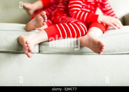 Feet of siblings (2-3, 4-5) in red pajamas Stock Photo