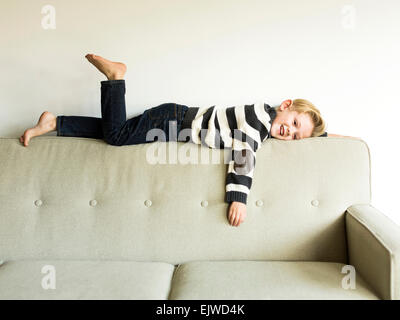 Boy (6-7) lying on sofa Stock Photo