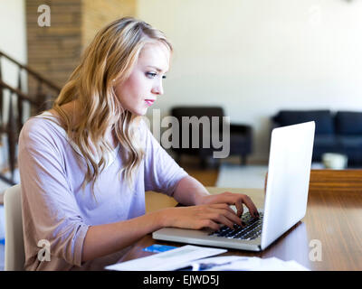 Young woman using laptop at table Stock Photo