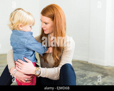 Mother sitting on floor embracing boy (2-3) Stock Photo