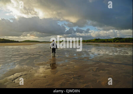 Ireland, County Mayo, Clew Bay, Rear view of man standing water in rubber boots, clouds in sky Stock Photo