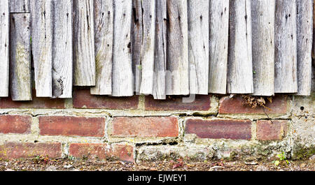 Weathered fence panels against a brick wall Stock Photo