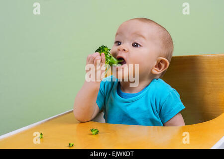 adorable baby eating broccoli Stock Photo