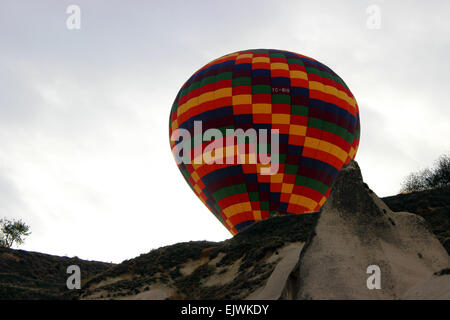 Hot air balloon rising from the valley behind the hill, Goreme, Cappadocia. Stock Photo