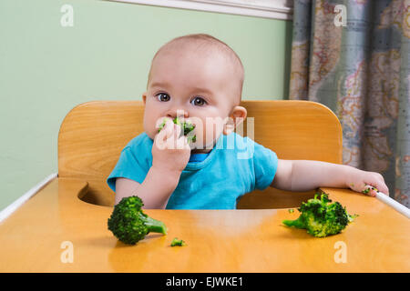 Cute baby eating broccoli Stock Photo