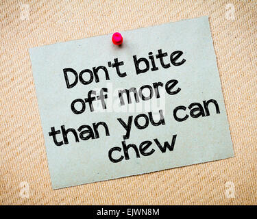 Don't bite off more than you can chew Message. Recycled paper note pinned on cork board. Concept Image Stock Photo