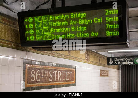 Subway train arrivals schedule shown on a digital readout at East 86th Street station Stock Photo
