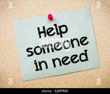Help someone in need Message. Recycled paper note pinned on cork board. Concept Image Stock Photo