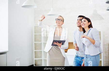Pretty realtor showing new flat to young couple Stock Photo